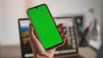Unknown businesswoman holding greenscreen mobile phone at home workplace closeup
