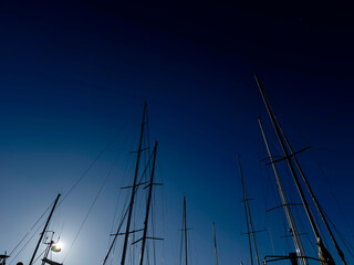 Masts of sailboats without sails against the blue sky.