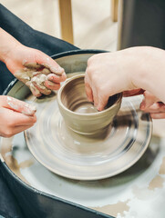 Child making ceramic vase on rotating pottery wheel at workshop. Creativity and traditional crafts concept. 