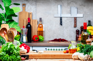 Healthy vegan eating, cooking, food blogging banner background with cutting board with garlic, tomato and other vegetables and herbs on cozy kitchen with wooden table, kitchenware and utensils