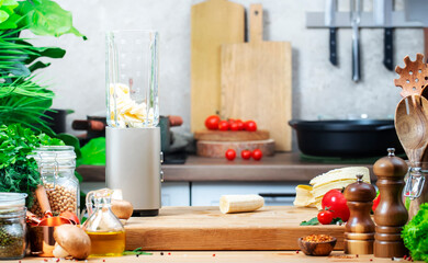 Healthy vegan eating, cooking, food blogging banner background. Blender and peeled bananas for smoothies on oak cutting board with in cozy kitchen with wooden table, kitchenware and utensils