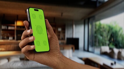 GREEN SCREEN CHROMA KEY A modern indoor living room setting during the day, with a person holding a phone. Ideal for apps showcasing home or tech-related features