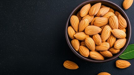   A green leaf sits beside a bowl of black almonds
