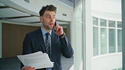 Fototapeta premium Mad businessman yelling smartphone looking documents in office corridor closeup.