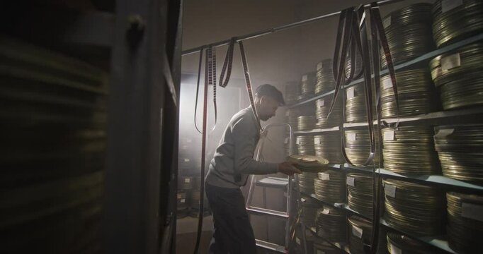 Elderly Archivist Sorting and Searching Vintage Film Reels in a Dusty Archive