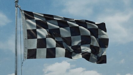 A checkered flag waving against a cloudy sky, symbolizing a race.