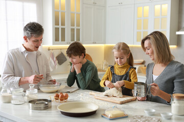 Happy family making dough at white marble table in kitchen