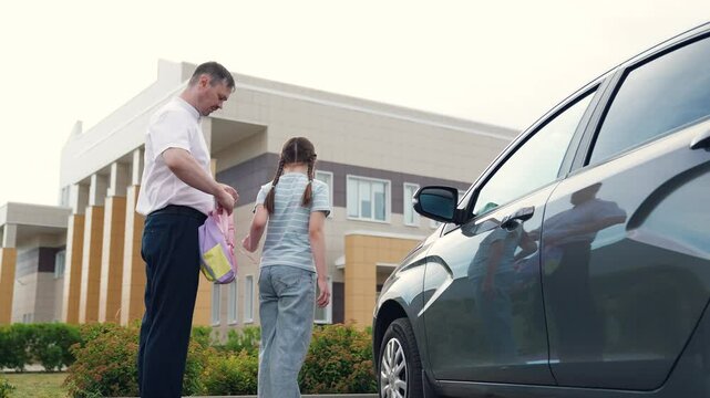 caring father by car sees child kid girl daughter school, happy family, school building background, father helps child kid girl daughter put backpack, girl with school backpack goes school, man father