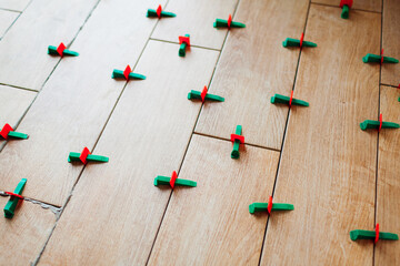 Tile leveling system with plastic clips and wedges. Wood effect narrow tiles installed on floor....