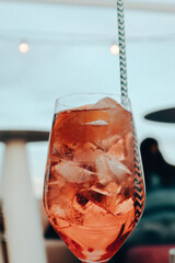 Aperol Spritz in the glass with a beverage tube. Urban party lifestyle. Alcoholic cold drink with...