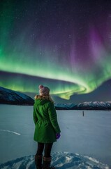 Woman admiring northern lights in snowy landscape