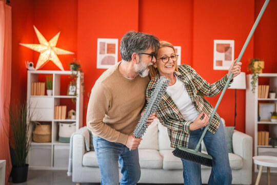 mature couple have fun while use cleaning tool like music instruments
