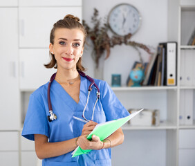 Portrait of friendly female doctor wearing uniform and stethoscope with folder