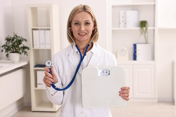 Weight loss. Smiling nutritionist with stethoscope and scales in clinic
