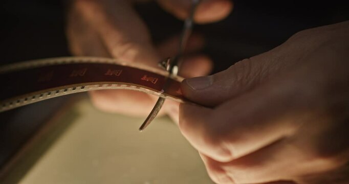 Film Editor Cutting and Splicing Vintage Film Reel in a Dark Archive