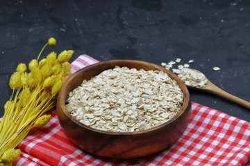 Oat flakes uncooked in a brown bowl on wooden table. Healthy food for breakfast