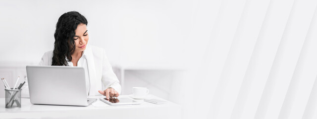 Reading News. Happy brazilian manager lady sitting at desk working with a tablet, copy space
