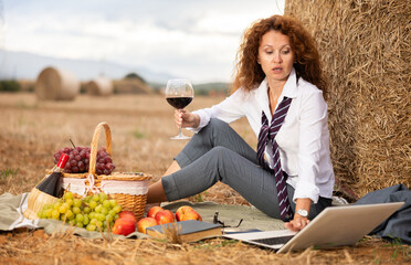 Relaxed woman in loosened tie, white shirt and trousers, escaping from hectic office life, drinking...