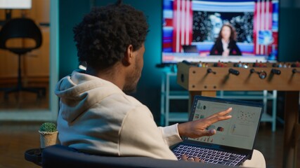 African american person working from home and checking statistical data on laptop screen, analyzing...