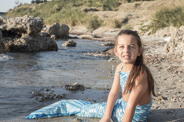 Young girl portrait in mermaid costume on the beach near sea