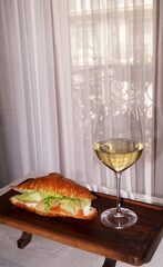 croissant with salad and salmon and white glass of wine