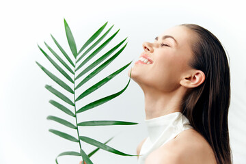 Naklejka premium Beautiful young woman with palm branch, smiling joyfully, natural beauty concept, bright background, spring vibes, lifestyle photography.