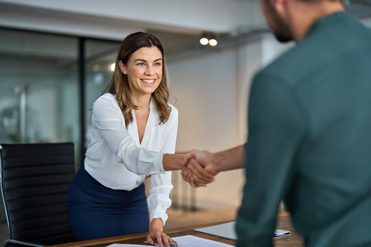 Business handshake concept. Happy middle aged professional woman manager and male client or partner shaking hand expressing trust in b2b partnership at meeting in corporate office. Hiring, onboarding.