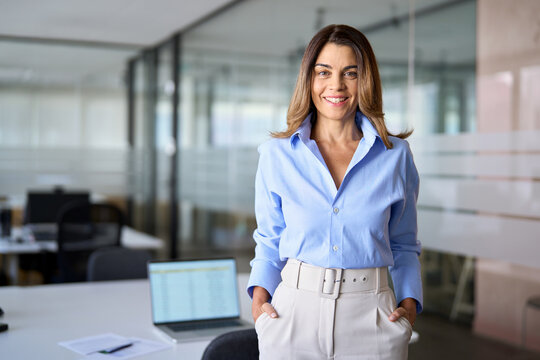 Smiling middle aged business woman, older female entrepreneur, happy mature female professional executive manager leader standing in modern company office looking at camera, portrait.