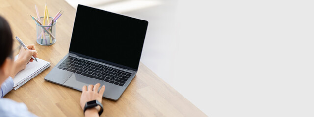 High angle view asian woman using laptop computer with blank screen mockup copy space, taking notes...