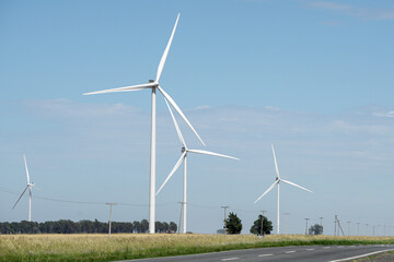 Wind farms with modern white windmills in rural road area