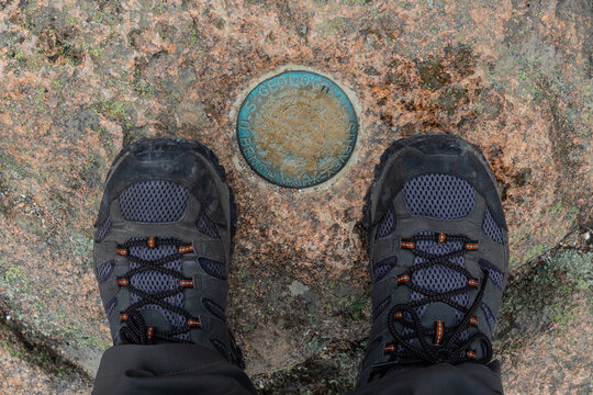 Worn hiking boots on a weathered rock at the U.S. Geological Survey Marker on Cadillac Mountain in Acadia National Park, Maine.