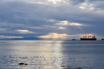 Obraz premium Serene Ocean Scene With Cargo Ships and Sunlight Near Stanley Park, Vancouver