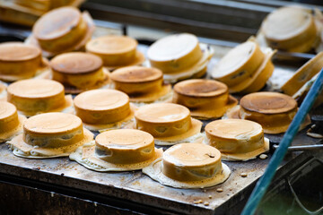a vendor in the process of making hot and steaming wheel cakes