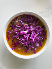 Warm winter soup with purple cabbage in a white bowl