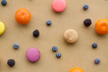 Colorful Macarons with Berries and Citrus on Plain Background