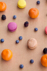 Colorful Macarons with Berries and Citrus on Plain Background