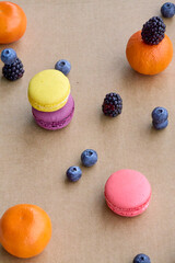 Colorful Macarons with Berries and Citrus on Plain Background