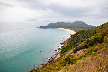 Fototapeta premium Serene Coastal Landscape with a Curved Beach in a Cloudy Day