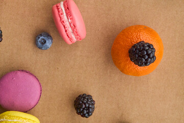 Colorful Macarons with Berries and Citrus on Plain Background