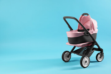 Doll stroller on light blue background, space for text. Kid's toy