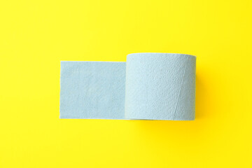 Light blue toilet paper roll on yellow background, top view