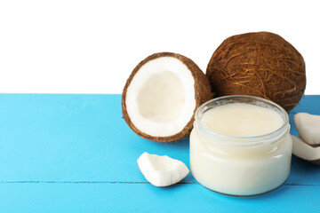 Coconuts and cooking oil on light blue wooden table against white background