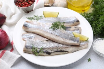 Marinated herring fillets with lime and dill on grey table, closeup