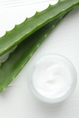 Cream and aloe leaves on white wooden background, flat lay