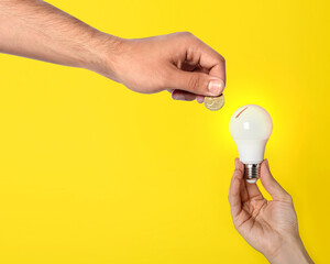 Find sponsor. Man offering coin to woman with light bulb on yellow background, closeup. Sponsorship...