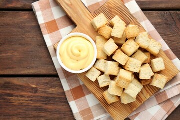 Delicious crispy croutons with sauce on wooden table, top view