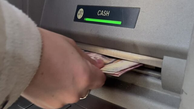 Close up video. Female hand picks up pack of paper banknotes from gray metal ATM in Tbilisi. Opened lid to dispense cash money. Bill. Concept of salary, cost, debt, tax, loan. Bank note 100 GEL. Lari