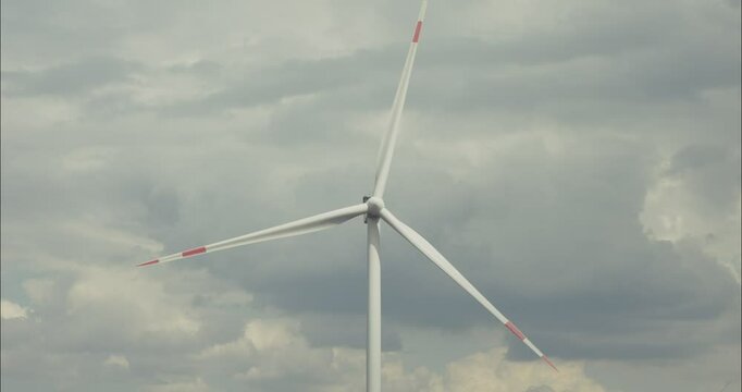 Wind turbine rotating blades under cloudy sky