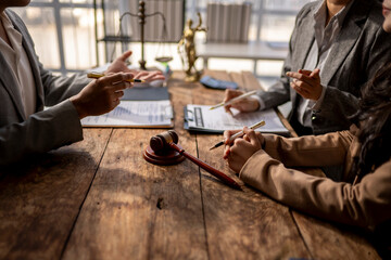 Three people are sitting at a table with a gavel and pens