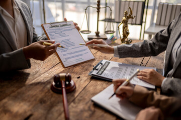 Three people are sitting at a table with legal documents in front of them